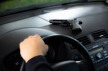 Theft of the car. Man with gun behind the wheel. Carjacking of vehicle. Robbing and crime.