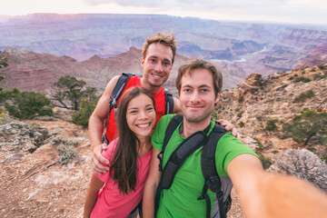 Selfie group of tourists friends hikers hiking outdoor. Happy people taking self portrait photo together in Grand Canyon nature park travel vacation. Group of three : Asian woman, two young man.