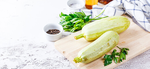 Fresh zucchini on a wooden board with a knife