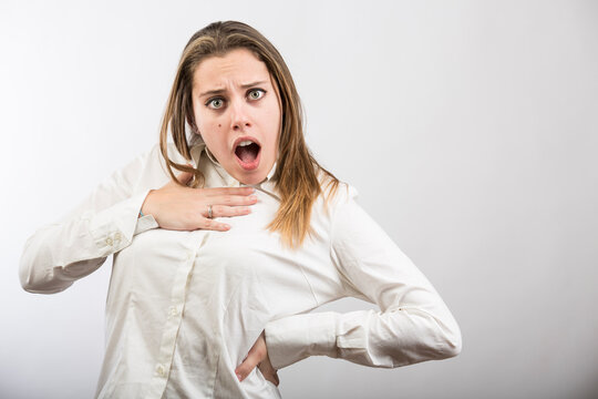 ragazza bionda con camicia bianca fa delle smorfie per dimostrare stupore assoluto, isolata su sfondo bianco