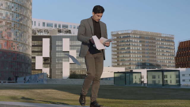 Businessman reading documents on street. Professional walking outdoors