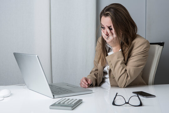Manager donna in giacca si dispera lavorando di fronte al computer nella sua scrivania