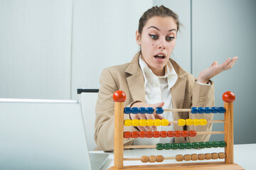 ragazza bionda vestita con una giacca beige è seduta nella sua postazione di lavoro , mentre cerca...