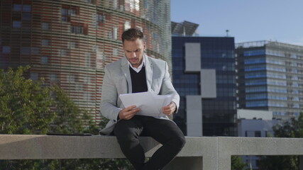 Fototapeta premium Businessman looking graphs on documents at street. Entrepreneur going for work