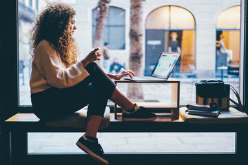 Young pondering female person with beautiful curly hair checking account balance on...