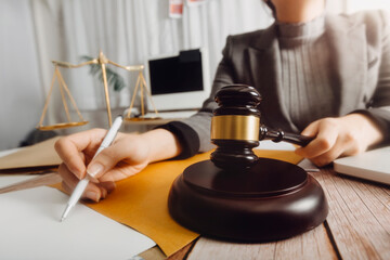 Justice and law concept.Male judge in a courtroom with the gavel, working with, computer and docking keyboard, eyeglasses, on table in morning light