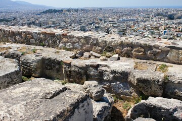 Greece, Athens, July 16 2020 - View of ancient stones at the archaeological site of the Acropolis, with modern buildings in the background.