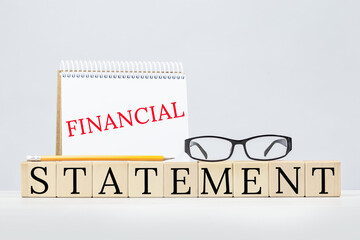 Financial statement text with eyeglasses and a notepad. Financial activities and position of business, person or entity. Business and finance concept on grey. Copy space