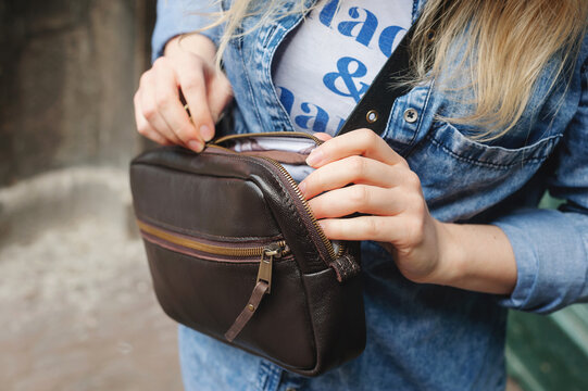 Dark brown leather bag. The girl takes something out of the bag. Leather Cross Body Bags For Women. Close-up.