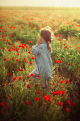 
a girl walking in a poppy field