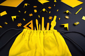 A concept on the subject back to school. The student's yellow stationery on a black background