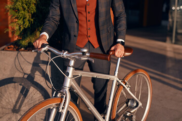 Fototapeta na wymiar Stylish businessman with bicycle standing on city street