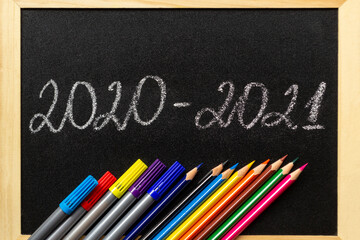 Inscription 2020-2021 on chalk blackboard. And frame from pencils and felt-tip pens down below.  Back to school and new academic year concept.