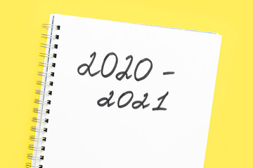 The inscription 2020 - 2021 in a white notebook with a spiral, on a yellow background. Concept of the new school year and return to school. Back to school