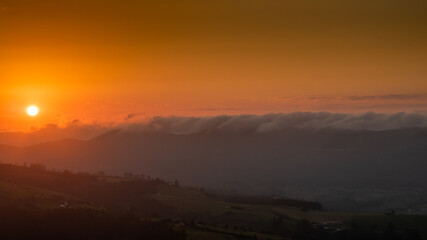 sunset between clouds and mountains in summer
