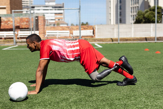 Mixed race male football player with prosthetic leg at a sports field - Powered by Adobe