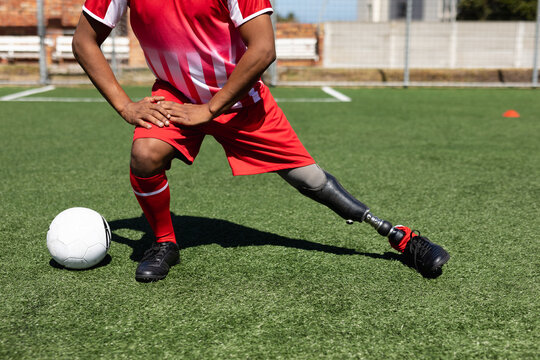 Mixed race male football player with prosthetic leg at a sports field - Powered by Adobe
