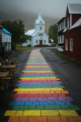 Rainbow street and Seydisfjardarkirkja church in Seydisfjordur town in East Iceland in rainy day