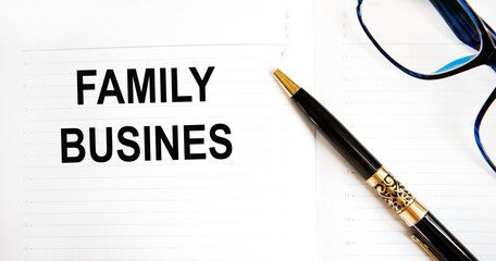 White note with inscription 'family business' on beautiful wooden table, colored paper, metalic pen. Business concept.