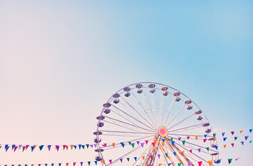 Ferris wheel with cloudless sky in background, color toning applied, space for text.