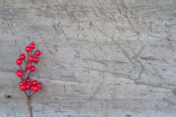 Christmas holiday greeting background. Red holly berries twig on rustic wooden background. Space for text, flat lay