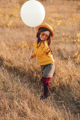 Naklejka na ściany i meble Stylish child with balloon in dry field