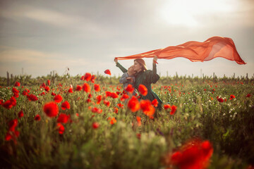 mom and daughter on a poppy field in the rays of the setting sun
