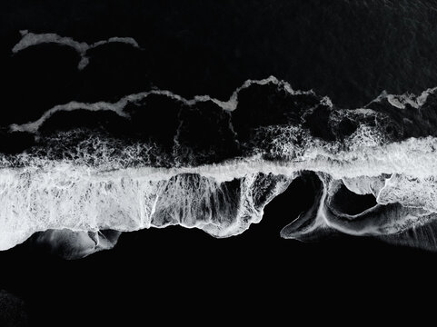 Fototapeta Aerial drone view of Reynisfjara Black Sand Beach and ocean waves in South Iceland near Vik village at sunset. Abstract nature background