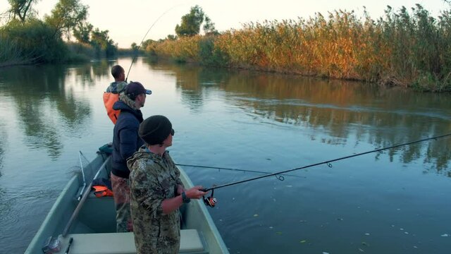 Anglers fishing from the boat floating on the river. Astrakhan region, Russia