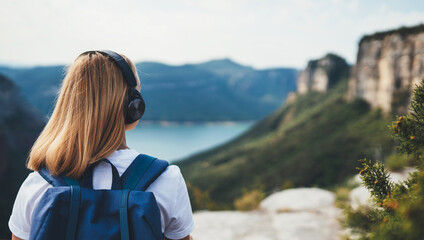 blonde woman meditating listening to music with headphones looking view landscape top of mountain, female tourist with long blond hair leisure after walk hiking and enjoy vacation trip, copy space