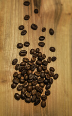 a handful of brown coffee beans on a light wooden background