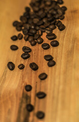 a handful of brown coffee beans on a light wooden background
