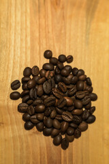a handful of brown coffee beans on a light wooden background
