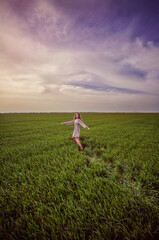 
A girl runs across a green field in spring