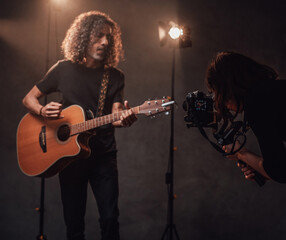 Videographer shoots how a talented Latin American musician playing guitar in the studio with stage lights