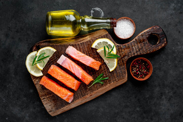 pieces of raw salmon with spices and lemon on a stone background