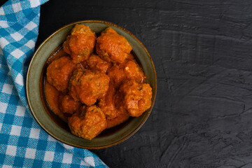 Meatballs in red sauce on dark background