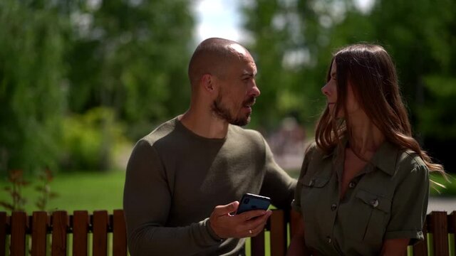 married couple is spending time together in park at summer weekend, man and woman are chatting