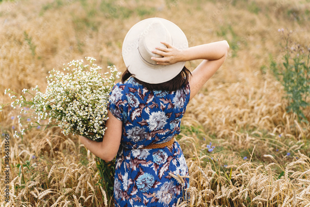 Wall mural beautiful girl with big daisies bouquet, back view. tranquil summer in countryside. stylish young wo