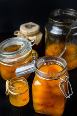 Jar with sweet apricot jam and fresh fruit on black table.Closeup.