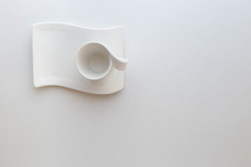 Empty espresso coffee cup with wavy saucer on white background