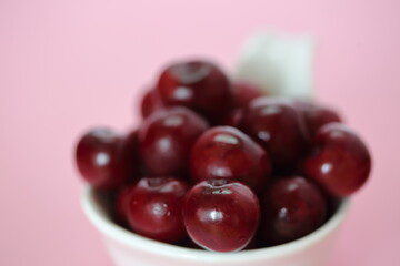 cherries in a bowl close up on pink background
