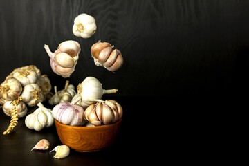 Garlic Cloves and Bulb in vintage wooden bowl.  Healthy food. Garlic on a wooden background. Traditional spices.