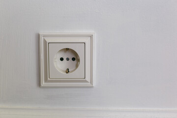 White plastic outlet with grounding on a gray background. Wall with copy space