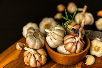 Garlic Cloves and Bulb in vintage wooden bowl.  Healthy food. Garlic on a wooden background. Traditional spices.