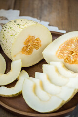 Ripe melon is cut on a dish on an old wooden table and an embroidered towel. Retro style, rustic