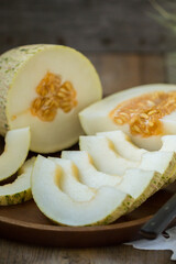 Ripe melon is cut on a dish on an old wooden table and an embroidered towel. Retro style, rustic