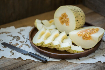 Ripe melon is cut on a dish on an old wooden table and an embroidered towel. Retro style, rustic