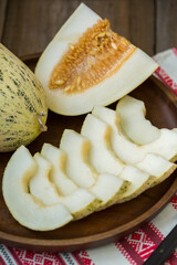Ripe melon is cut on a dish on an old wooden table and an embroidered towel. Retro style, rustic