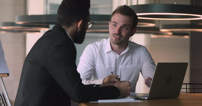 Confident male caucasian financial consultant adviser expert talking to arab client customer explain commercial investment deal benefit show computer presentation at bank loan negotiation meeting